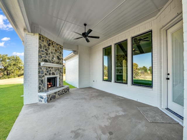 view of patio with an outdoor stone fireplace and ceiling fan