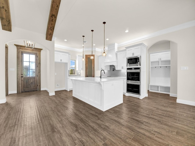 kitchen featuring decorative light fixtures, dark hardwood / wood-style floors, stainless steel microwave, and an island with sink