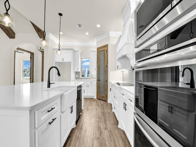 kitchen with tasteful backsplash, a center island with sink, white cabinets, and plenty of natural light