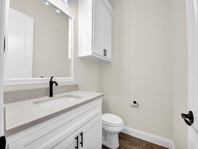 bathroom with wood-type flooring, vanity, and toilet