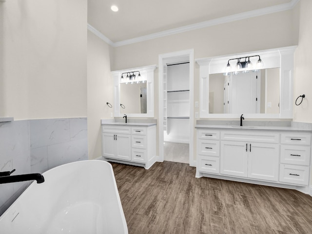 bathroom with crown molding, a washtub, vanity, and wood-type flooring