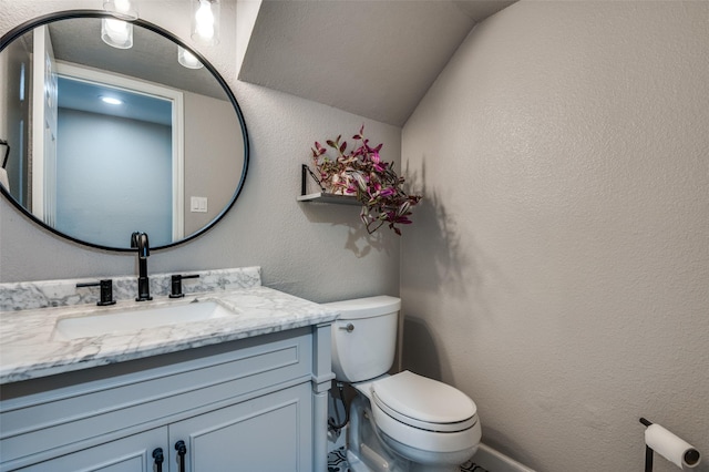 bathroom featuring vanity, toilet, and vaulted ceiling