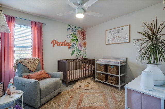 bedroom featuring a nursery area and ceiling fan