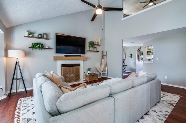 living room with a textured ceiling, high vaulted ceiling, ceiling fan, and dark wood-type flooring