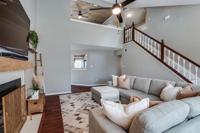 living room featuring a tile fireplace, ceiling fan, high vaulted ceiling, and wood-type flooring