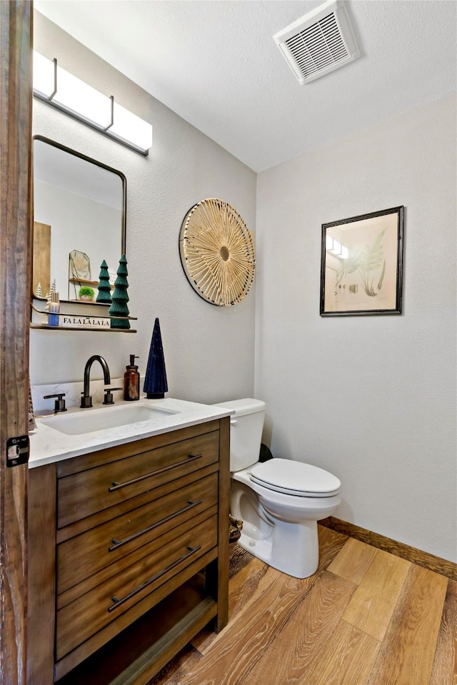 bathroom featuring hardwood / wood-style flooring, vanity, toilet, and a textured ceiling