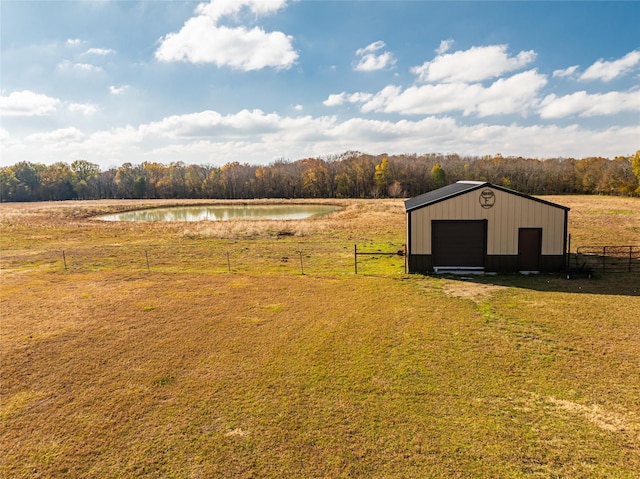 exterior space featuring a rural view, a garage, an outbuilding, and a water view