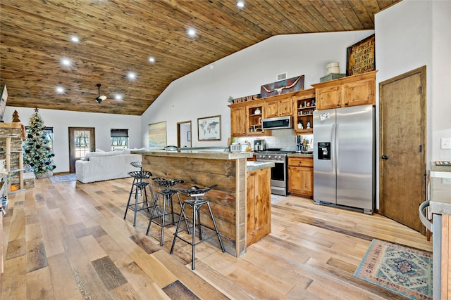 kitchen with high vaulted ceiling, stainless steel appliances, a kitchen breakfast bar, light hardwood / wood-style floors, and wooden ceiling