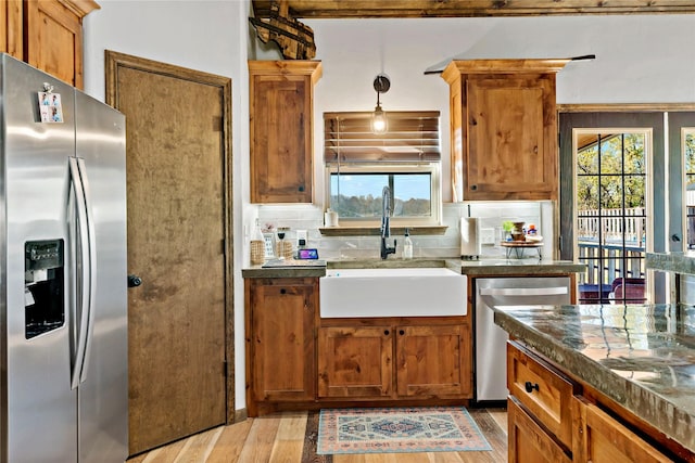 kitchen featuring sink, decorative light fixtures, appliances with stainless steel finishes, light hardwood / wood-style floors, and decorative backsplash