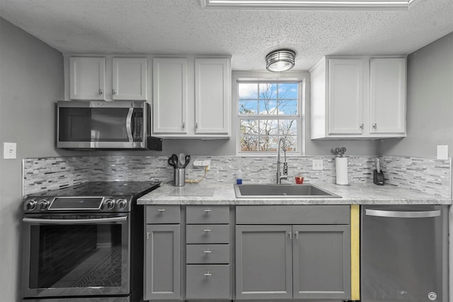 kitchen with tasteful backsplash, gray cabinetry, a textured ceiling, stainless steel appliances, and sink