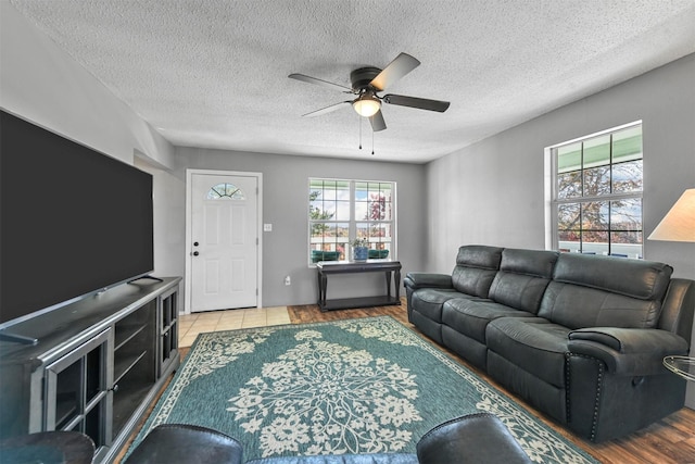 living room featuring ceiling fan, a textured ceiling, and light hardwood / wood-style flooring