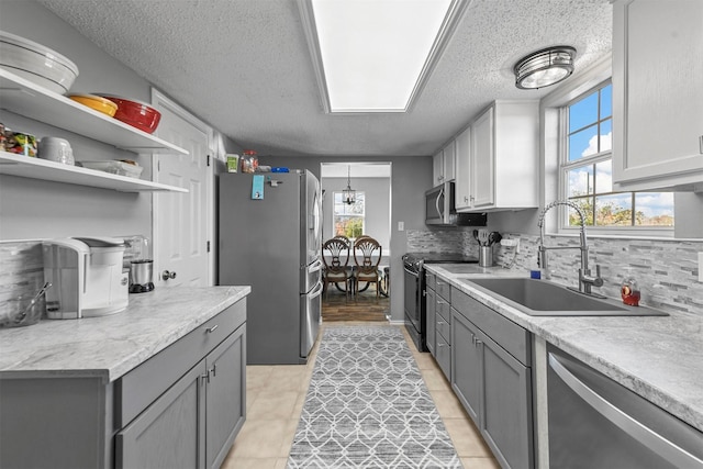 kitchen with backsplash, stainless steel appliances, sink, gray cabinets, and light tile patterned flooring