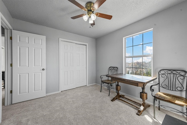 carpeted home office featuring ceiling fan and a textured ceiling