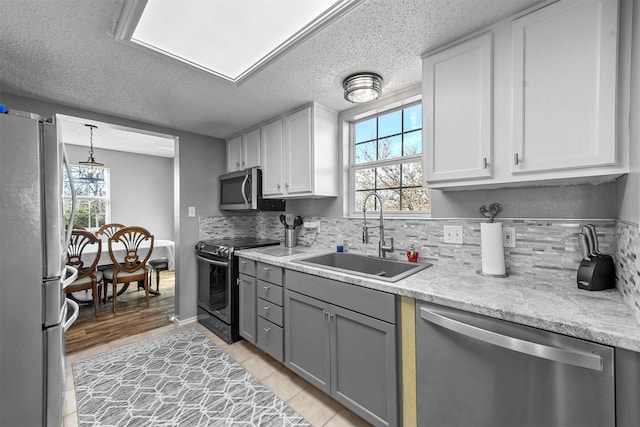 kitchen with backsplash, sink, a healthy amount of sunlight, and appliances with stainless steel finishes