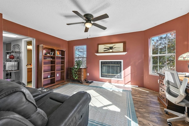 living room with ceiling fan, dark wood-type flooring, and a textured ceiling