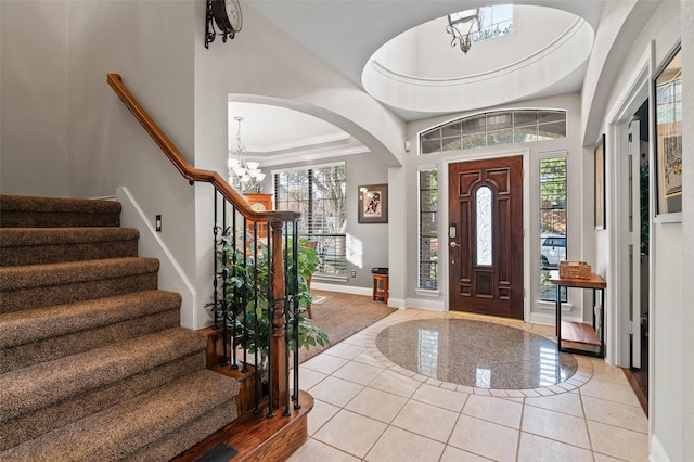 tiled foyer featuring a chandelier, a towering ceiling, and crown molding