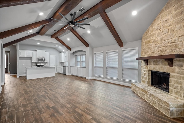 unfurnished living room featuring lofted ceiling with beams, a fireplace, ceiling fan, and dark wood-type flooring