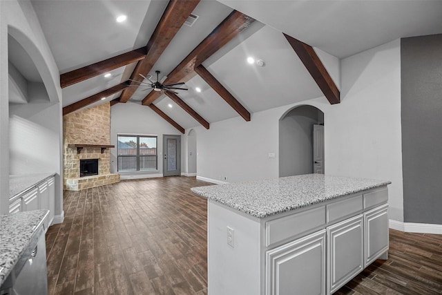 kitchen featuring dark hardwood / wood-style flooring, ceiling fan, a center island, white cabinetry, and a stone fireplace