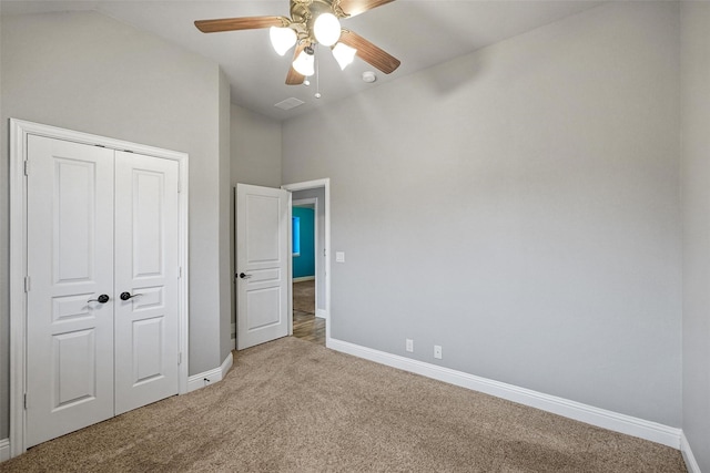 unfurnished bedroom with ceiling fan, a closet, carpet, and vaulted ceiling