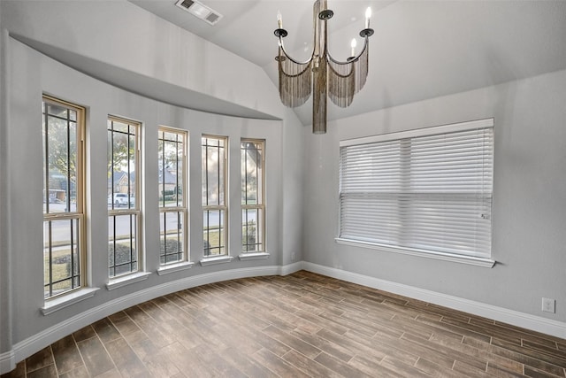 unfurnished room featuring hardwood / wood-style floors, an inviting chandelier, and lofted ceiling