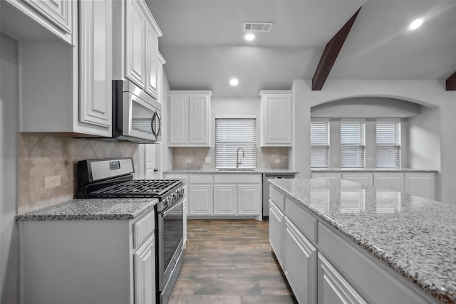 kitchen featuring sink, decorative backsplash, appliances with stainless steel finishes, dark hardwood / wood-style flooring, and white cabinetry