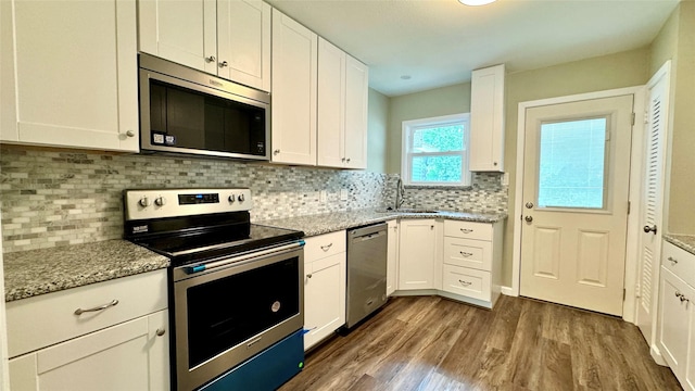 kitchen featuring sink, white cabinetry, light stone counters, dark hardwood / wood-style flooring, and stainless steel appliances