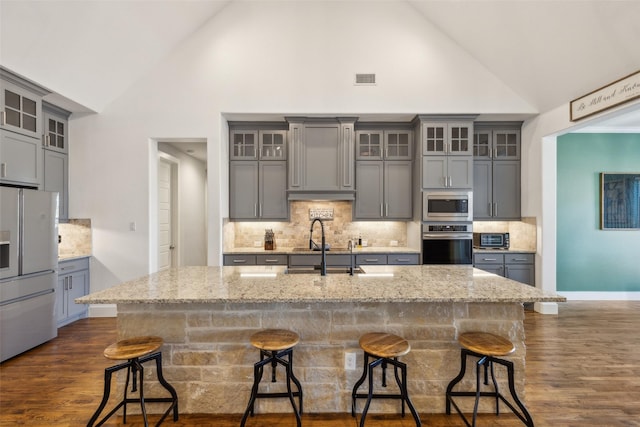 kitchen with a breakfast bar, stainless steel appliances, high vaulted ceiling, and dark hardwood / wood-style floors