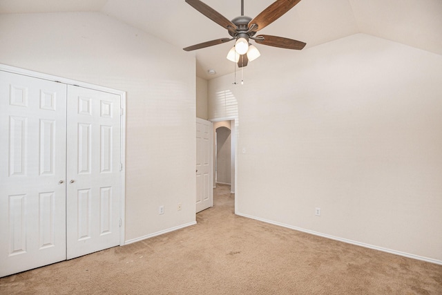 unfurnished bedroom featuring light carpet, a closet, ceiling fan, and vaulted ceiling