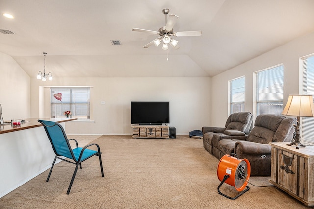 carpeted living room with a wealth of natural light, ceiling fan with notable chandelier, and lofted ceiling