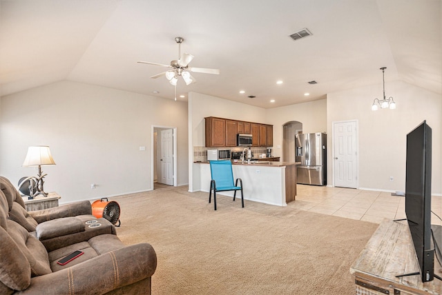 carpeted living room featuring ceiling fan with notable chandelier and vaulted ceiling