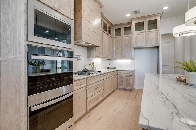 kitchen featuring stainless steel appliances, light stone counters, light wood-type flooring, light brown cabinetry, and custom exhaust hood