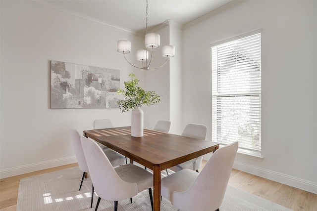 dining area with light hardwood / wood-style floors, crown molding, a wealth of natural light, and an inviting chandelier