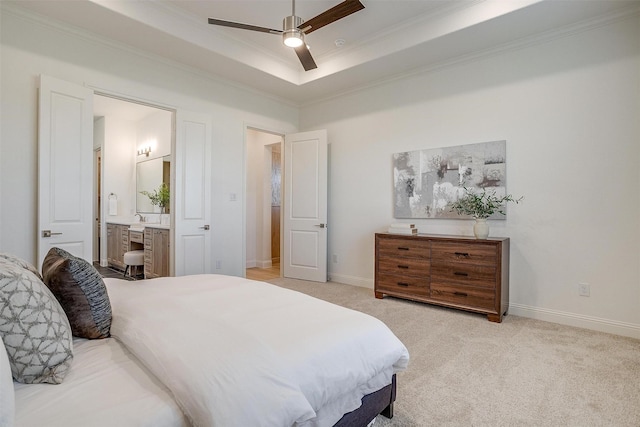 bedroom with ensuite bathroom, ceiling fan, ornamental molding, a tray ceiling, and light colored carpet