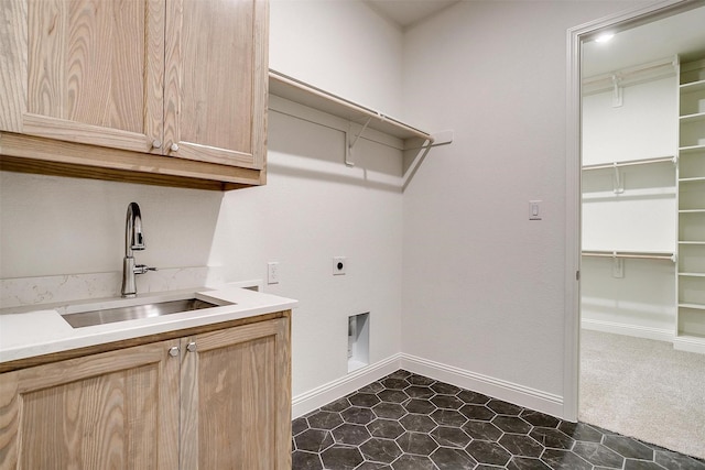 laundry area with dark tile patterned flooring, electric dryer hookup, cabinets, and sink