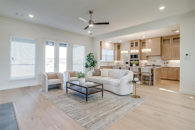 living room featuring ceiling fan, french doors, crown molding, and light hardwood / wood-style flooring