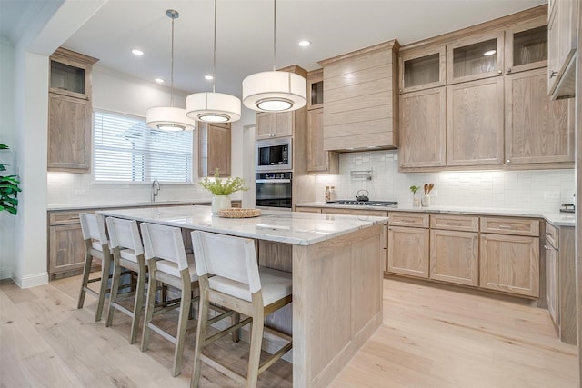 kitchen with a center island, backsplash, appliances with stainless steel finishes, and light hardwood / wood-style flooring