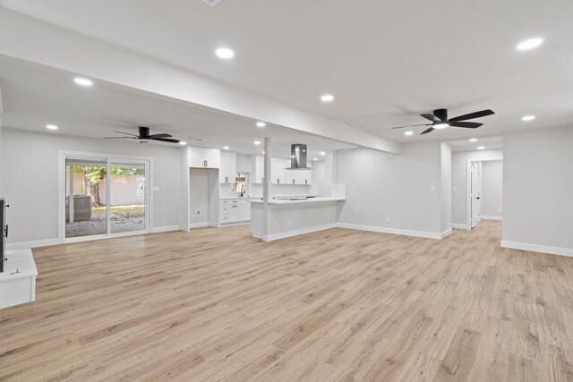 unfurnished living room featuring ceiling fan, sink, a fireplace, and light hardwood / wood-style flooring