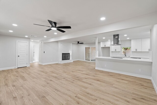 unfurnished living room with ceiling fan and light wood-type flooring