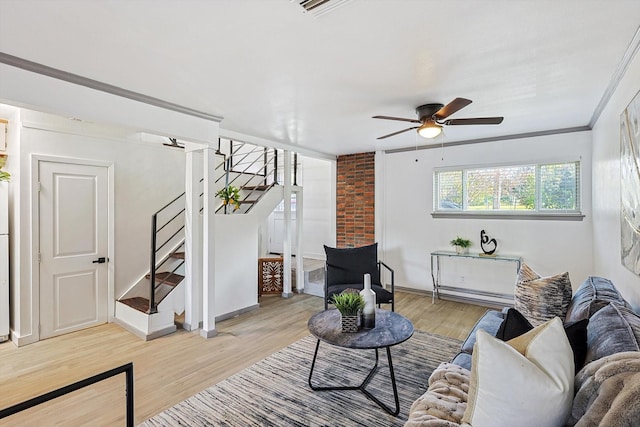 living room with ceiling fan, light wood-type flooring, and crown molding