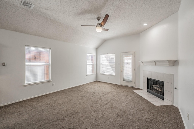 unfurnished living room with plenty of natural light, lofted ceiling, a fireplace, and light carpet