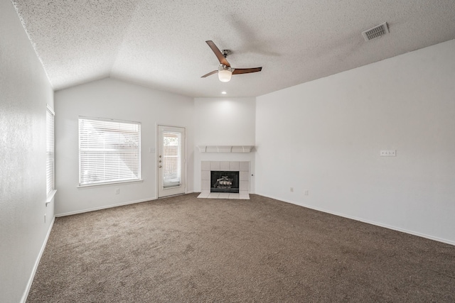 unfurnished living room with carpet, lofted ceiling, ceiling fan, a fireplace, and a textured ceiling