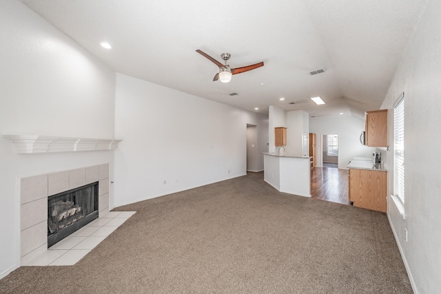 unfurnished living room featuring a fireplace, light colored carpet, and ceiling fan