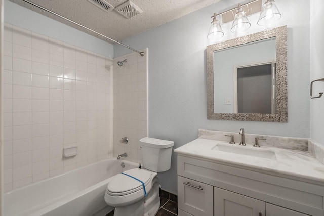 full bathroom featuring tile patterned flooring, a textured ceiling, toilet, vanity, and tiled shower / bath