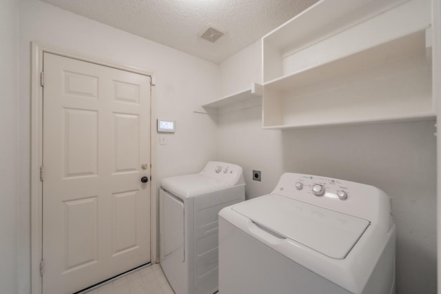 washroom with washing machine and dryer and a textured ceiling