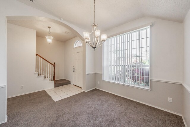 entryway with a textured ceiling, an inviting chandelier, light carpet, and vaulted ceiling