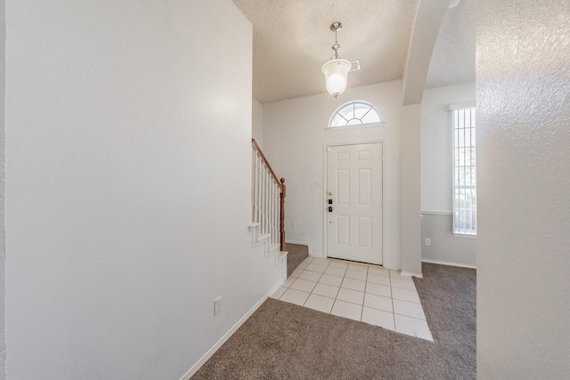 carpeted entryway featuring a textured ceiling and a healthy amount of sunlight