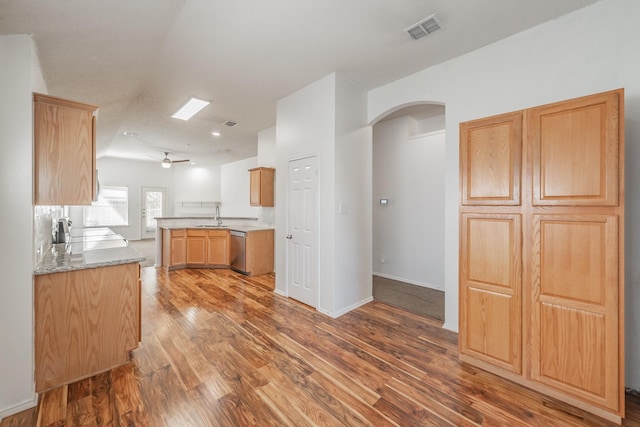 kitchen featuring ceiling fan, dishwasher, sink, light stone counters, and hardwood / wood-style floors