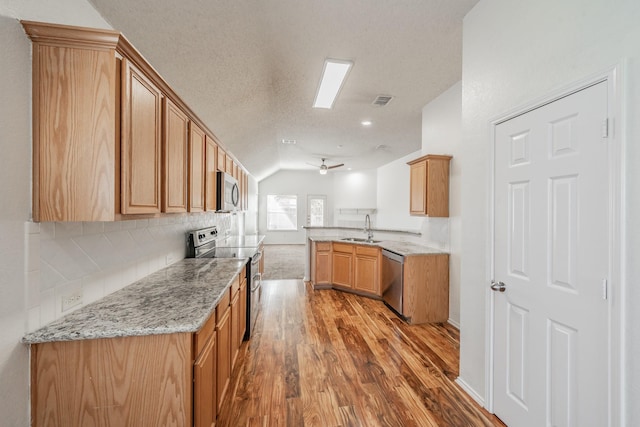 kitchen featuring sink, ceiling fan, a textured ceiling, light hardwood / wood-style floors, and stainless steel appliances