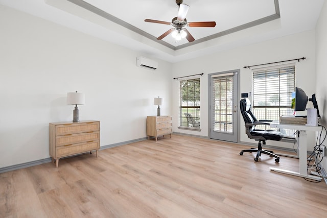 office area with a wall mounted AC, a healthy amount of sunlight, a raised ceiling, and light wood-type flooring