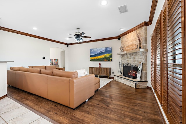 living room featuring ornamental molding, a stone fireplace, and hardwood / wood-style floors